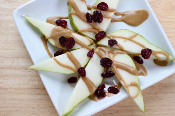 Easy to make pear nachos are a nutritious snack that will fuel any hungry tummy. Pear slices are simply topped with nut butter and dried cranberries.
