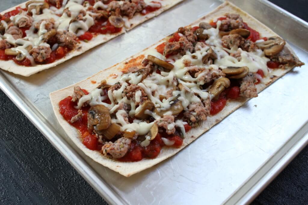img_3216 - Mom to Mom Nutrition Flatbread pizza crust is topped with a homemade pizza sauce and a hearty combination of sausage, mushrooms, and onions! Making pizza night light and flavorful!