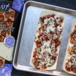 Flatbread pizza crust is topped with a homemade pizza sauce and a hearty combination of sausage, mushrooms, and onions! Making pizza night light and flavorful!