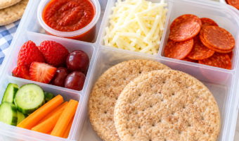 Homemade pizza lunchables with sandwich thins, pepperoni, mozzarella, pizza sauce, fruit, and vegetables