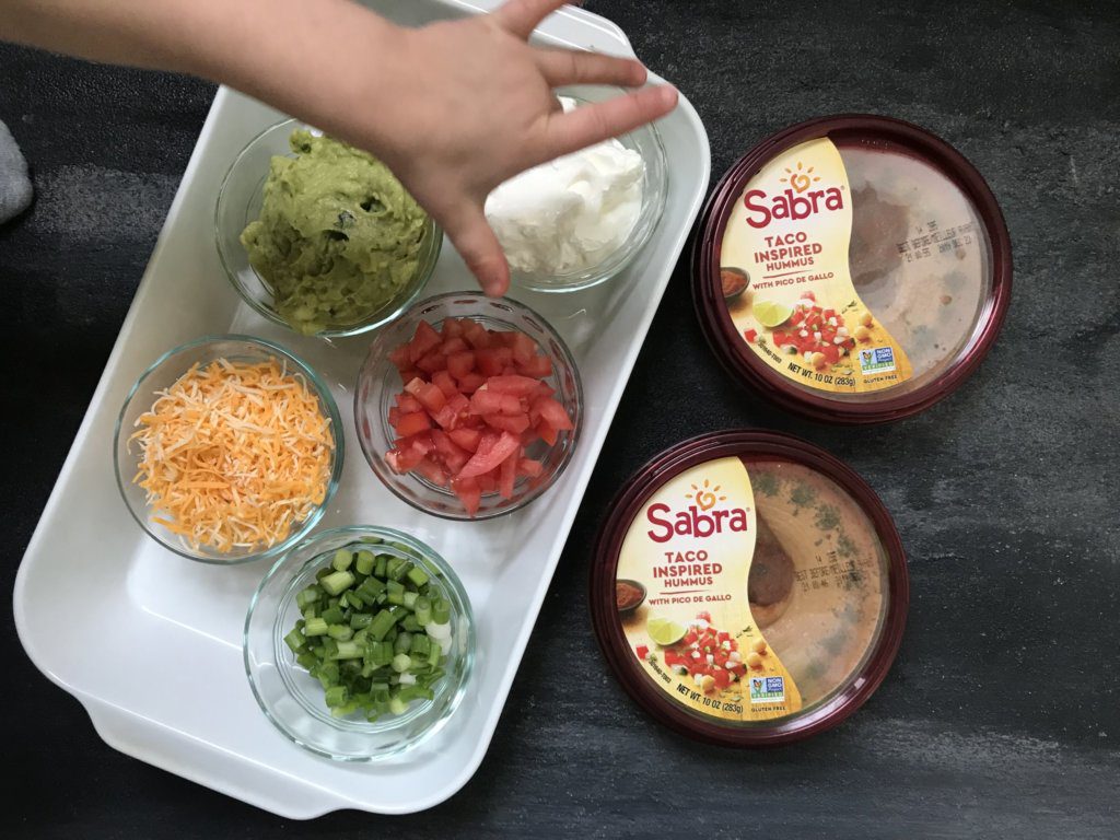 Taco-inspired Hummus Dip tastes exactly like eating a taco, but in hummus form! Made with Sabra taco hummus, this layered dip of all your favorite taco ingredients makes the perfect dip for any occasion. 