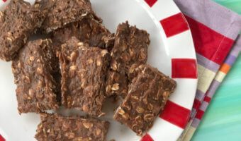 No-bake chocolate protein bars stacked on a white and red plate.