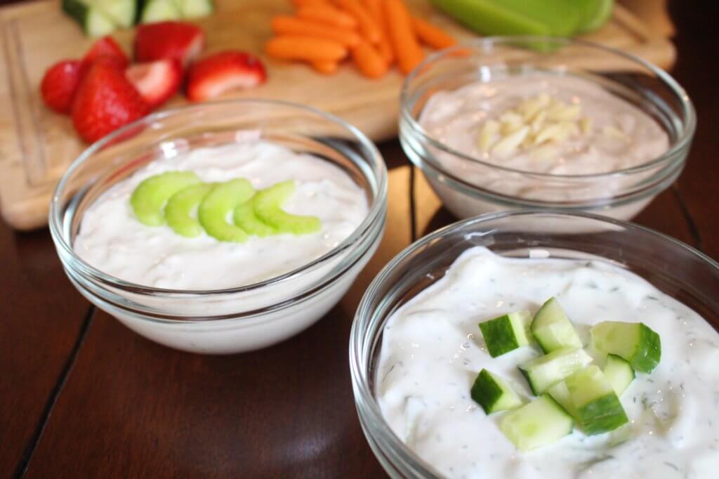 greek-yogurt-dip - Mom to Mom Nutrition Greek yogurt dip three ways with chopped fruits and veggies behind them.